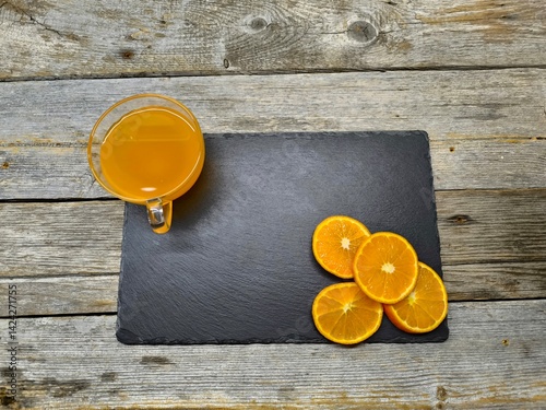 sliced ​​round tangerine slices lie on a granite board. Next to a cup of juice