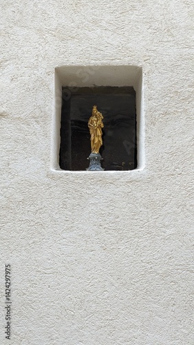 A golden statue of the Virgin Mary stands in a wall in the south of France.