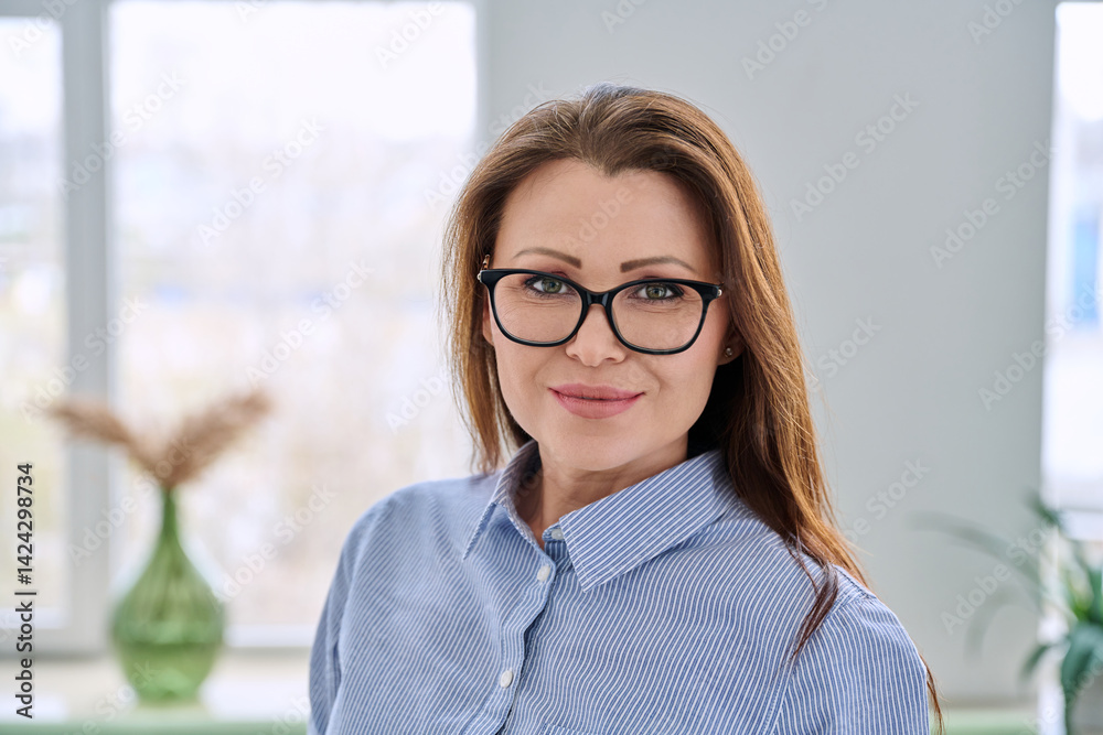 Headshot portrait of smiling businesswoman with glasses in blue shirt