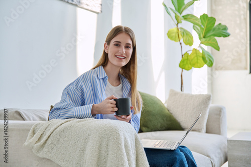 Obraz na płótnie Portrait of young beautiful smiling blonde woman with laptop sitting on sofa at home w salonie