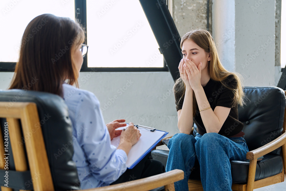 Sad upset young woman patient in therapy session in psychologist office
