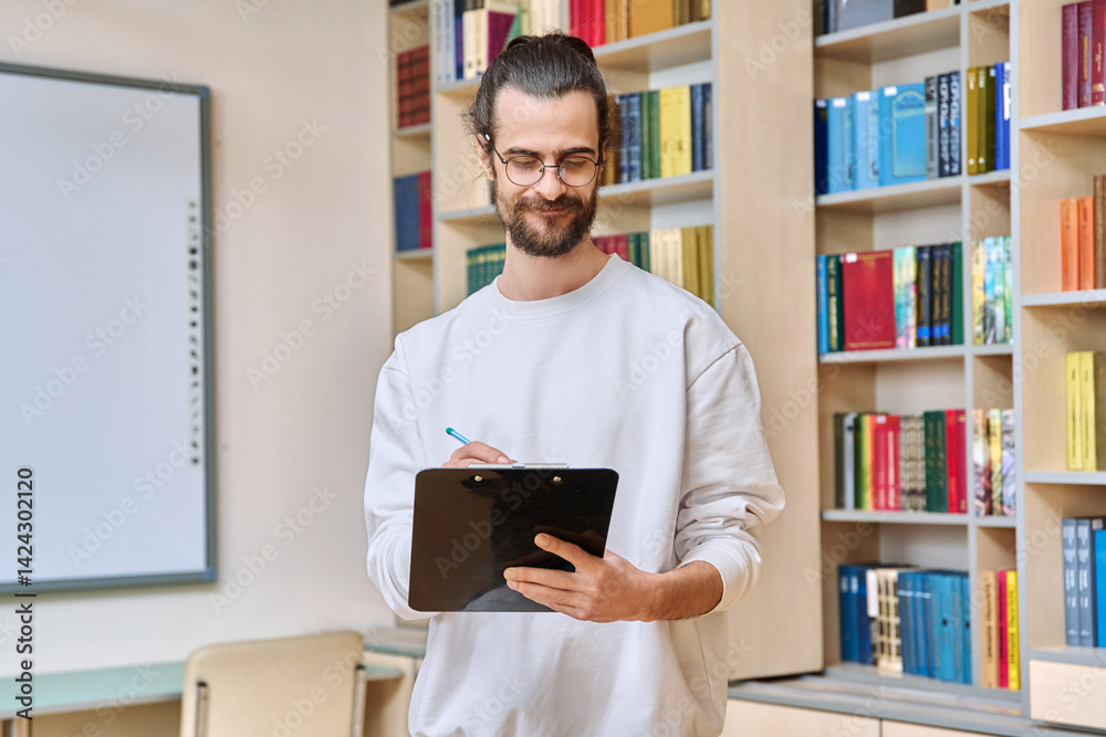 Portrait young male psychologist with clipboard in office library