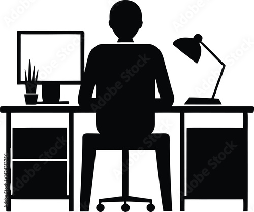 A silhouette of a businessman sitting at his office desk works on a laptop computer