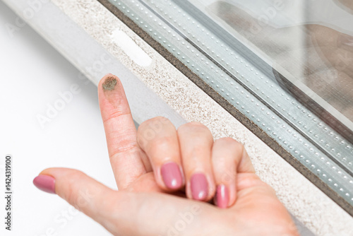 woman shows dirt accumulated on window, close-up. dirty plastic window. window glass cleaning. dirt on the tip of the finger