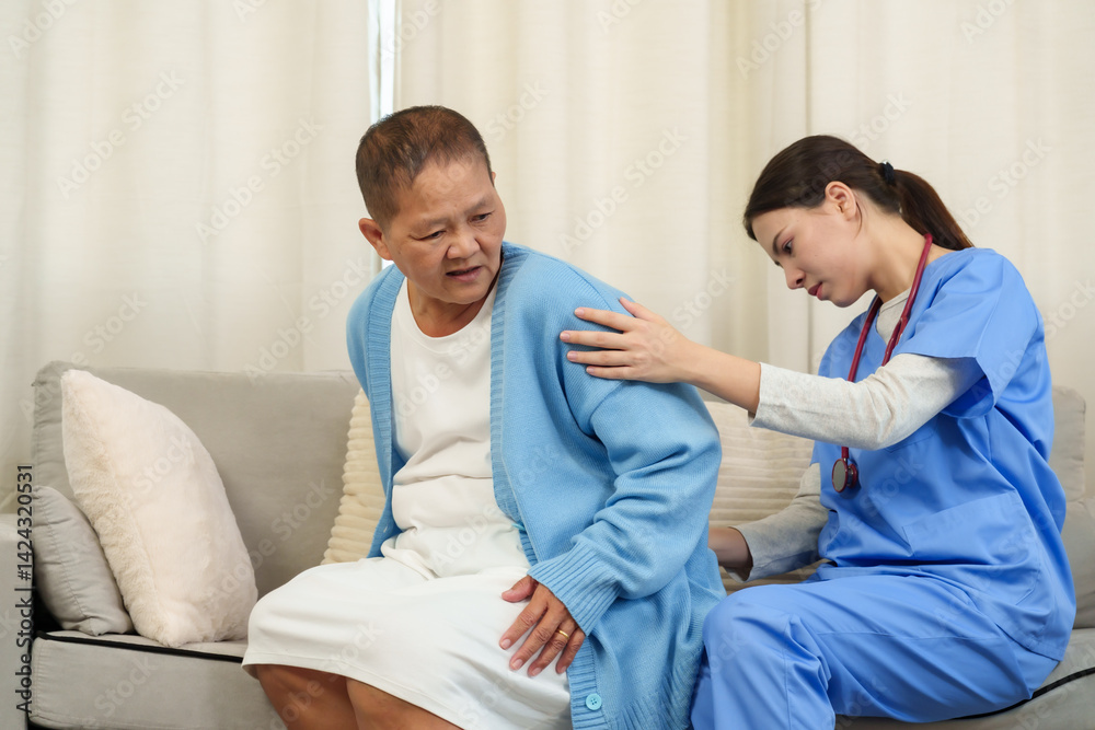 Obraz premium Young asian female physical therapist assisting elderly female patient with back pain during rehabilitation session on sofa applying hands-on care promoting support recovery posture improvement