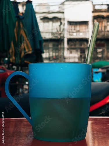 Blue Mug of Drink with Straw on a Red Table at an Outdoor Market.