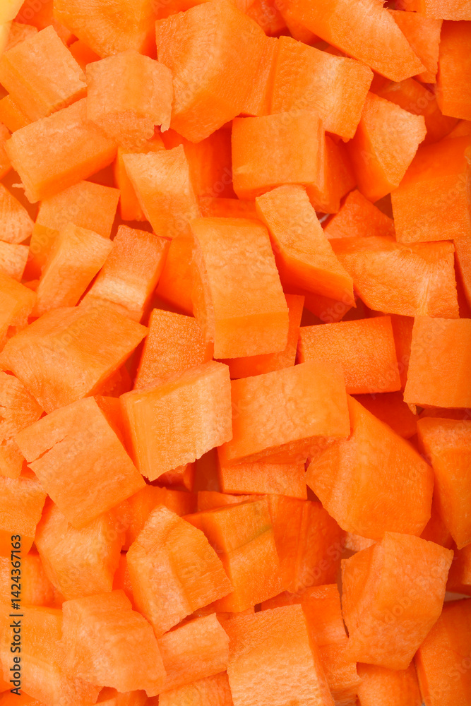 A close-up, top-down shot shows a dense pile of raw, vibrant orange diced carrots