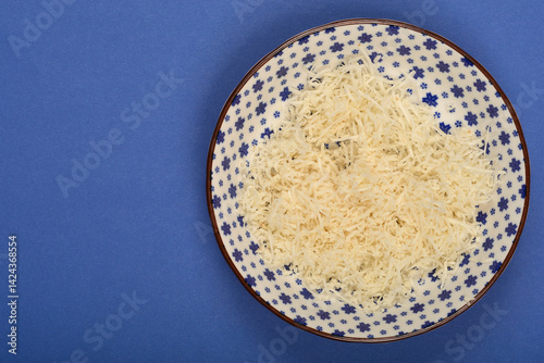Obraz na płótnie A patterned bowl contains a pile of freshly grated horseradish on a solid blue surface w salonie
