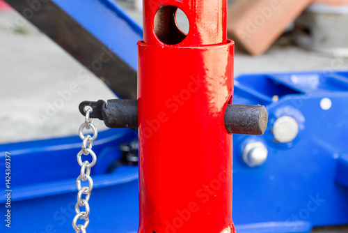 Close-up of the adjustable height locking pin and support column of a red jack stand, used for automotive maintenance and lifting vehicles safely. Car jack stand.