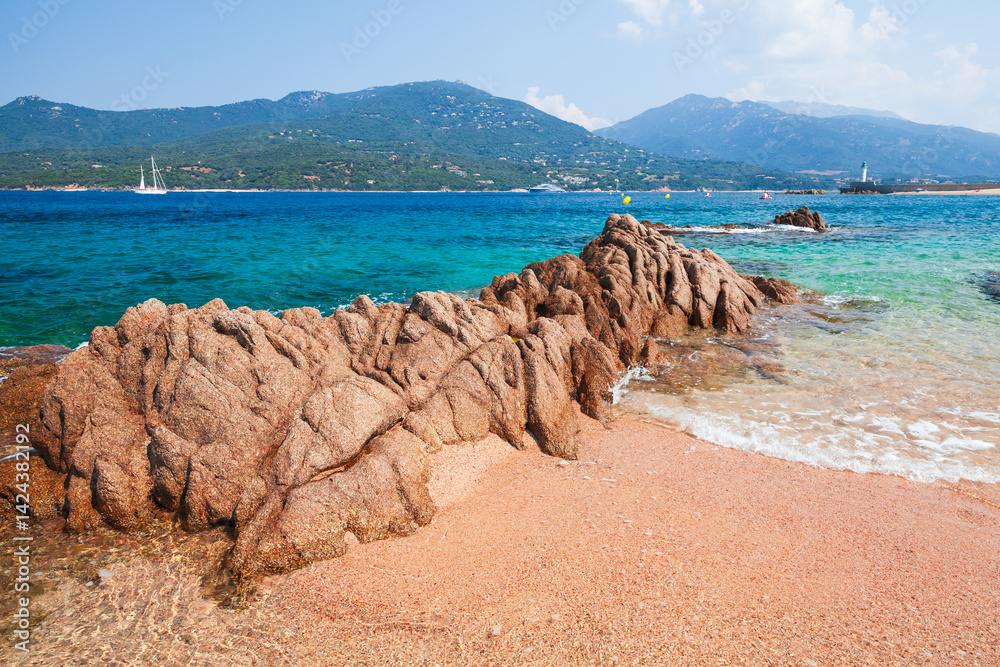 Scenic view of a rugged rocky shoreline beside crystal-clear waters. Corsica
