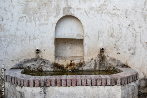 Old cement fountain with brick border and two spouts