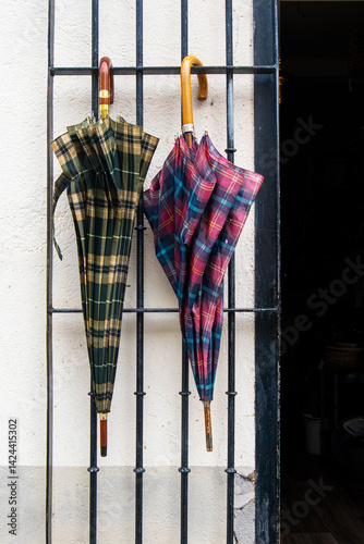 two umbrellas hanging from a fence at the entrance of a shop