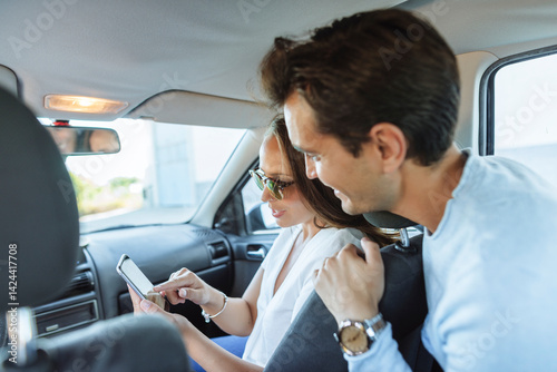 Couple traveling inside car looking at mobile phone