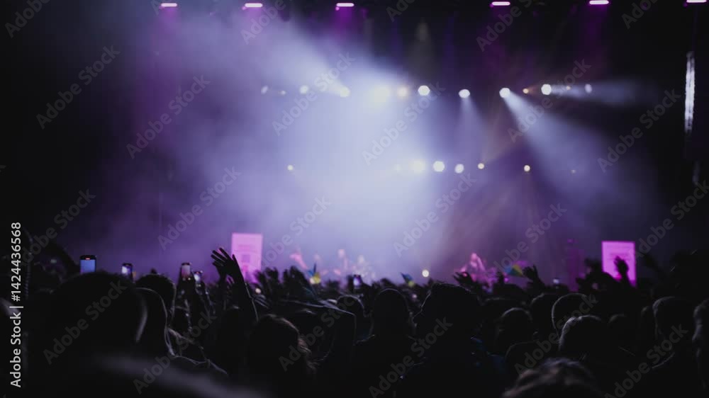 Perfect light show. Fans with rased your hands and wave for music against background white, blue and magenta spotlight on stage. Medium shot. Perfect light show. Fans with rased your hands and wave for music against background white, blue and magenta spotlight on stage. Medium shot.