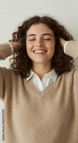 Obraz na płótnie Woman smiling with eyes closed and hands running through her hair against a white backdrop, showcasing happy and carefree concept. w salonie
