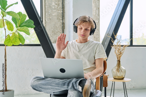 Obraz na płótnie Teenage boy with headphones using laptop for video conference, online meeting w salonie