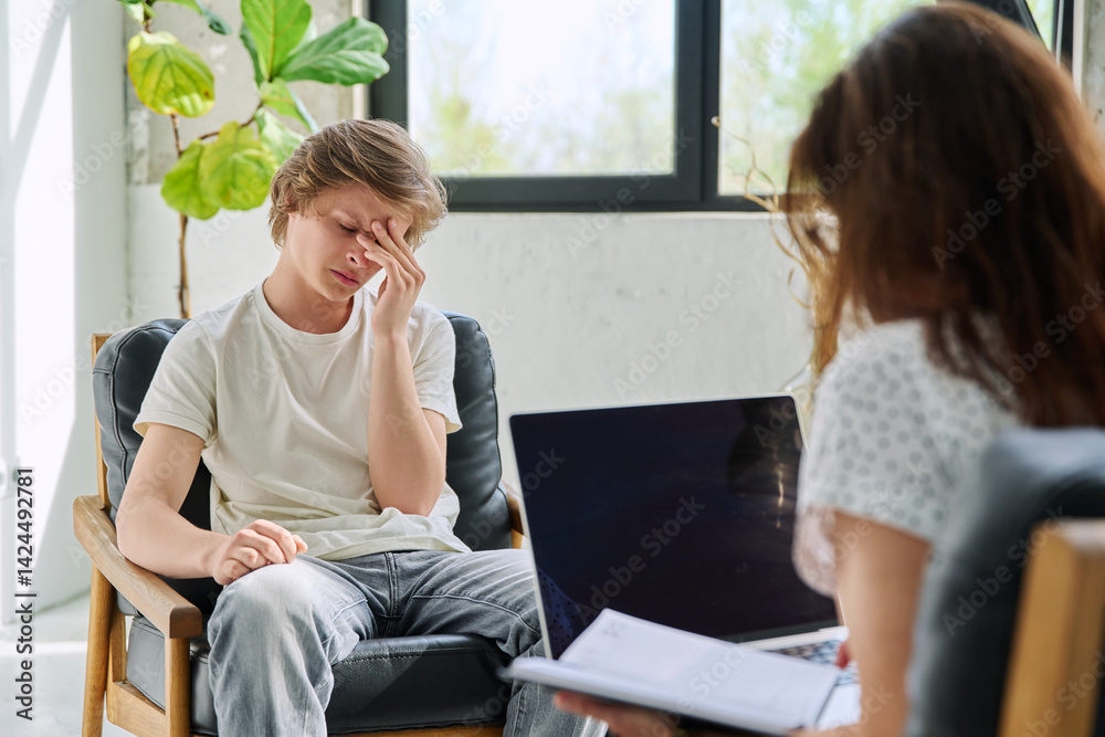 Sad teenage boy in mental therapy session, talking with behavioral psychologist