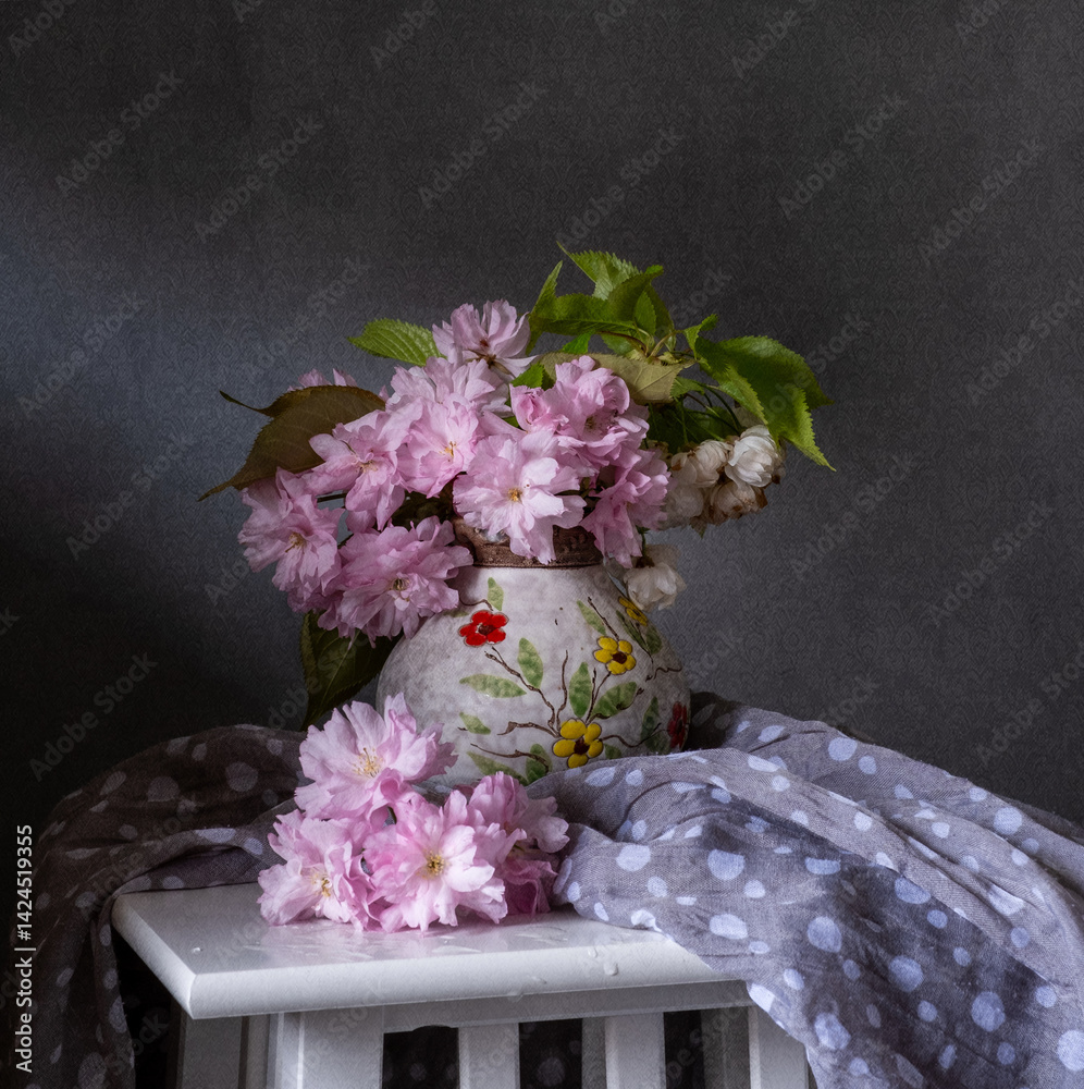 This is a beautiful spring floral arrangement featuring a bouquet of cherry blossoms and an element of delicate drapery.