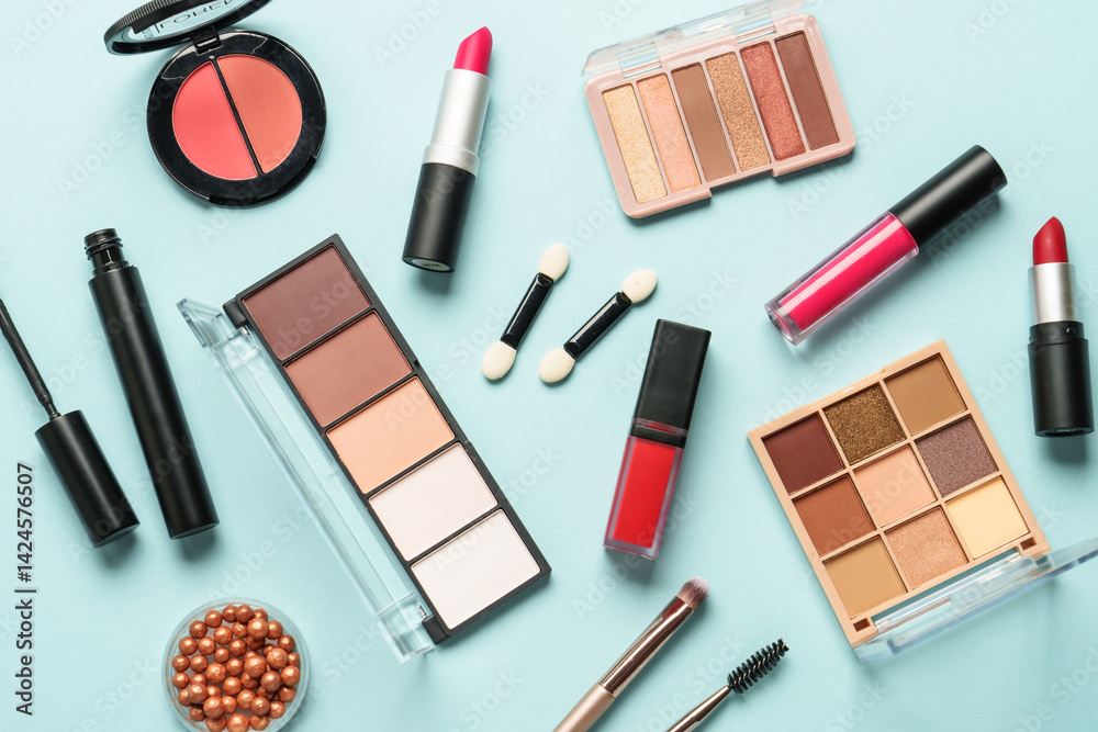 Beauty products on blue background. Cosmetic palette, brushes, cream and lipsticks. Top view.