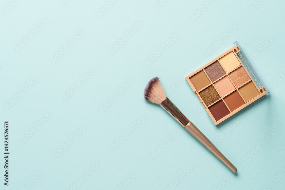 Make up products on blue background. Cosmetic palette, brushes and lipstick. Top view with copy space.