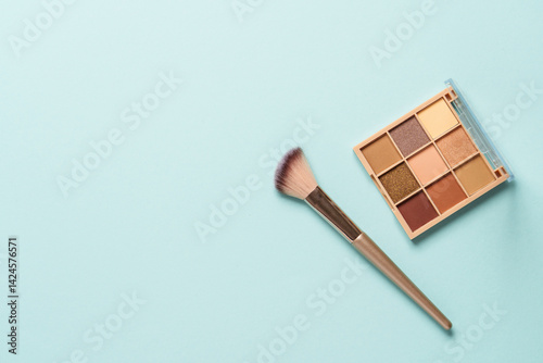 Obraz na płótnie Make up products on blue background. Cosmetic palette, brushes and lipstick. Top view with copy space. w salonie