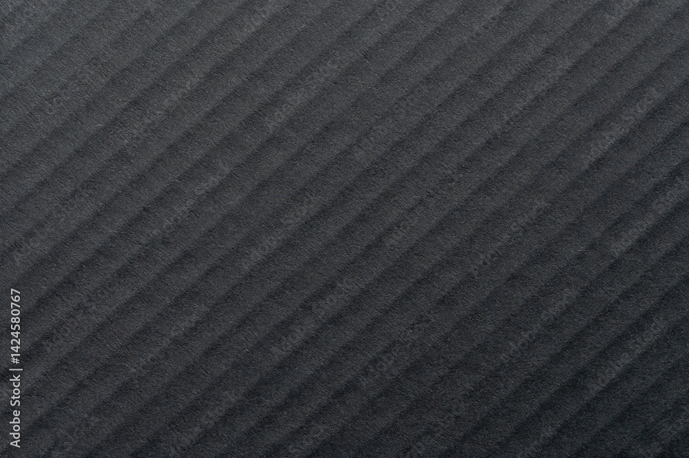 Textured black surface showcasing diagonal lines and shadows in natural light