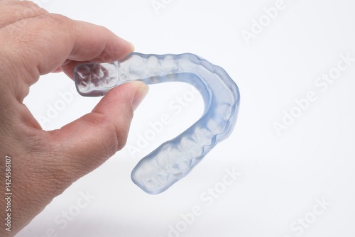 Doctor holding a clear dental night guard or mouthguard designed to protect teeth from grinding, promoting oral health and hygiene for patients