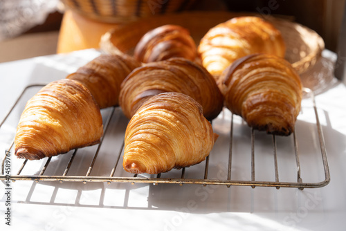 A cooked golden color of traditional French croissants in a baking tray. It's viennoiserie of Austrian origin. Made with a yeast leavened dough that has been laminated with butter in multiple layers.