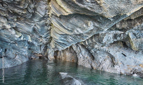 Interior of the flooded Marble Caves, unique rock formations in the General Carrera Lake, Chile. The walls of the caves have swirling mineral patterns. Turquoise water fills the caves with blue light.