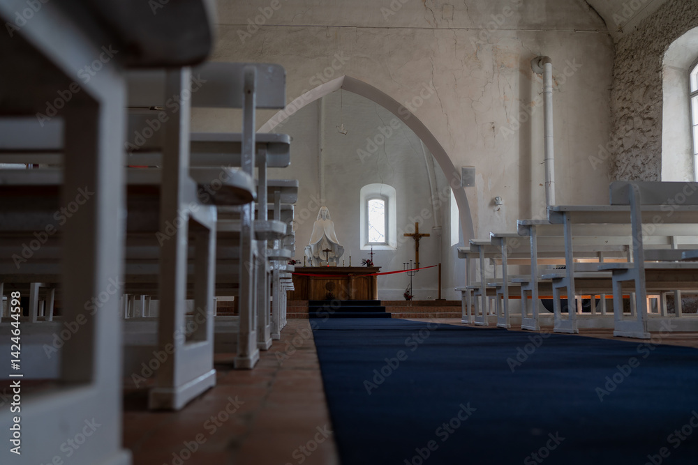 Obraz premium Interior of Old Lutheran Church with Altar. View of a historic Lutheran church interior with white pews, modest altar, and religious statue under natural light.