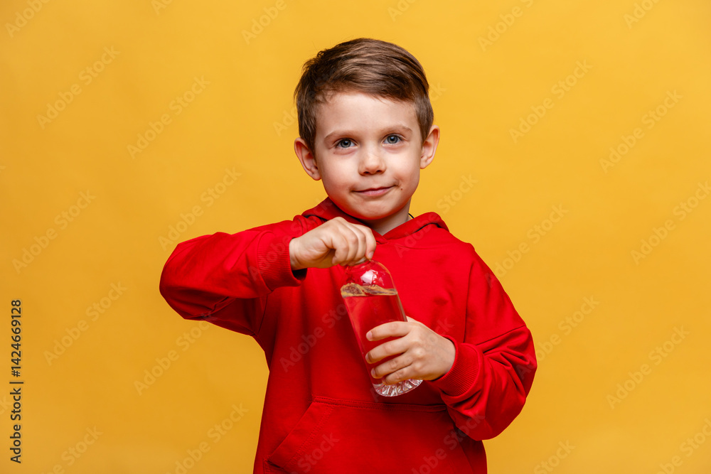Happy little boy drinks water for health on yellow background. The child is opening a bottle of water. A kid with a plastic bottle. Children's activity and energy, generation Z. body hydration concept