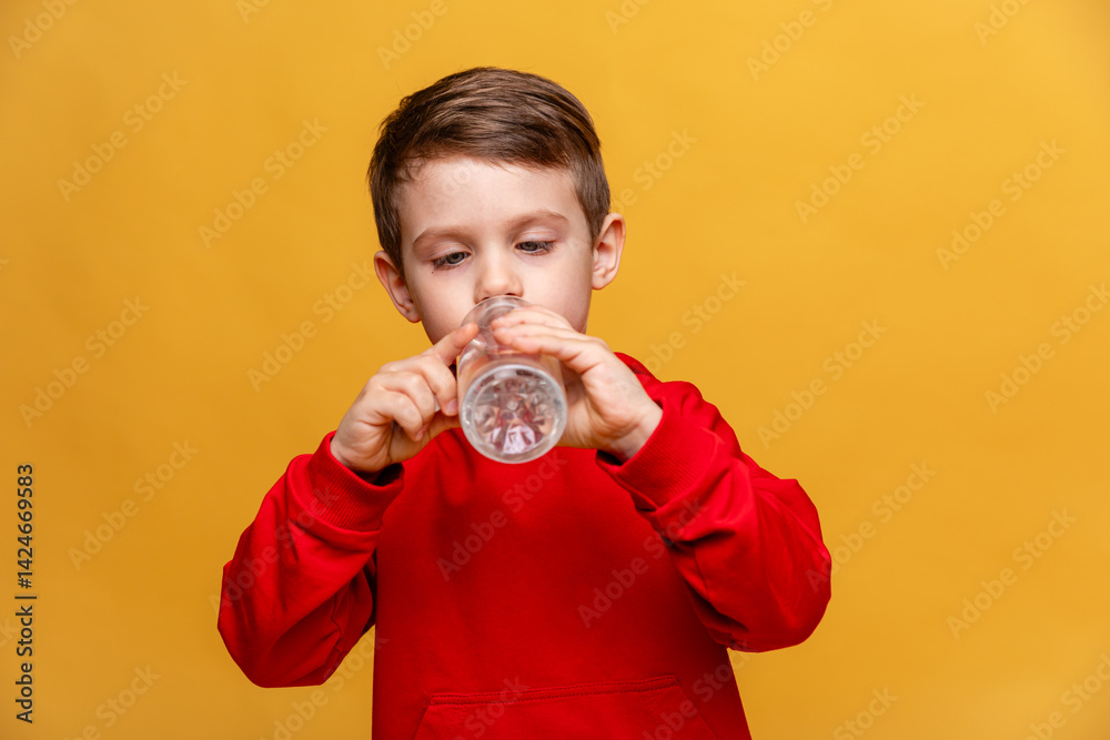 A happy little boy drinks water for health on yellow background. The child is holding a water bottle. A kid with a plastic bottle. Children's activity and energy, generation Z. body hydration concept