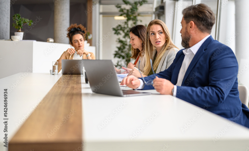 Businessman analyzing report over laptop and discussing with female colleague in professional meeting Businessman analyzing report over laptop and discussing with female colleague in professional meeting