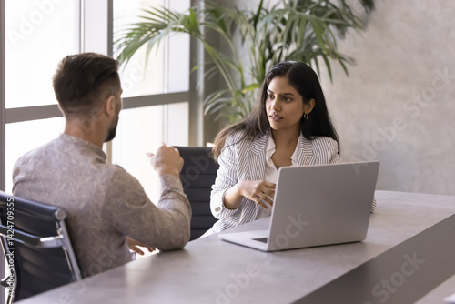 Two diverse businesspeople engaged in focused professional collaborative conversation, productive discussion related to joint task completion. Negotiation, formal meeting between manager and client