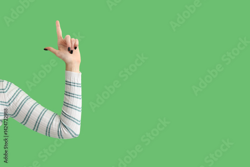 Hand of woman showing loser gesture on green background