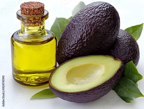 A small bottle of rich golden avocado oil sits beside two ripe avocados and a halved one showcasing its creamy flesh.