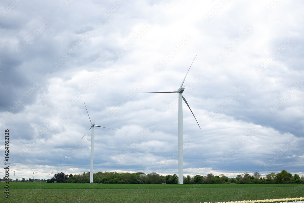 Tall wind turbines stand majestically against a vibrant sky, generating renewable energy amidst lush green fields. Tall wind turbines stand majestically against a vibrant sky, generating renewable energy amidst lush green fields.