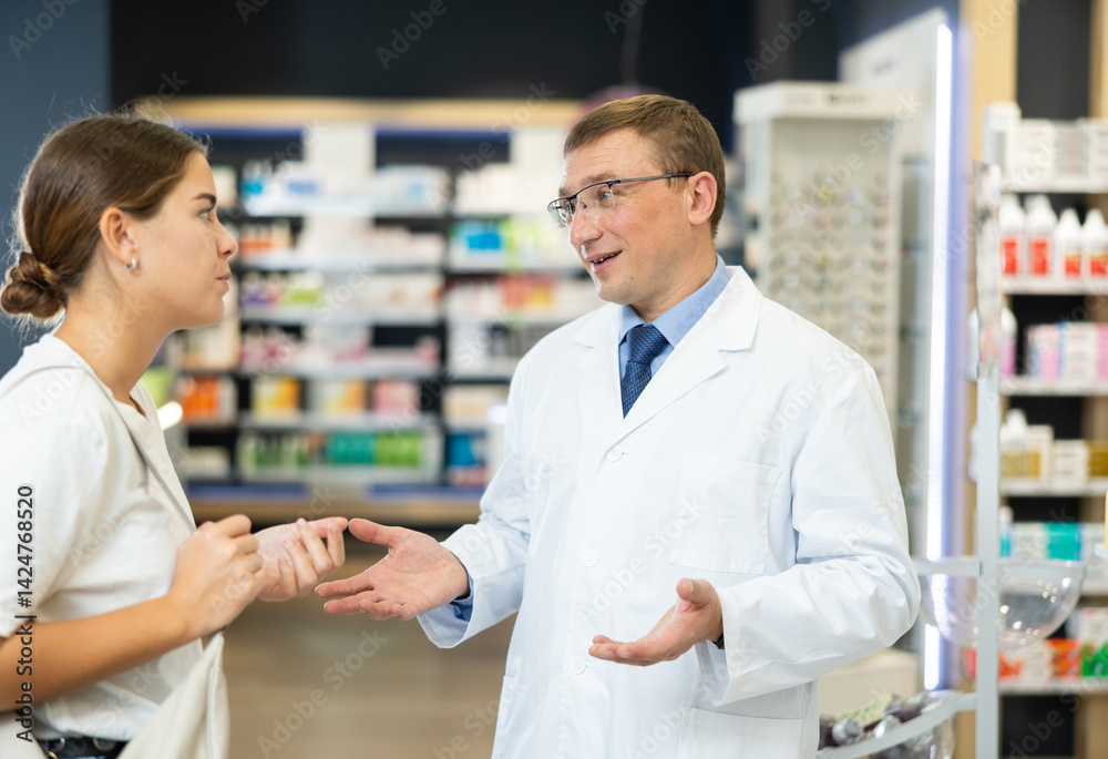 Obraz premium Male pharmacist and young female customer having conversation in a pharmacy