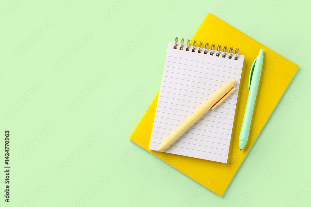 Office notebooks and pens on green background