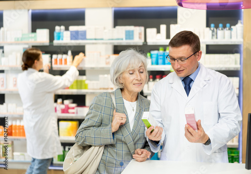 Obraz na płótnie Elderly woman client consults with a pharmacist which medicinal ointment to buy w salonie
