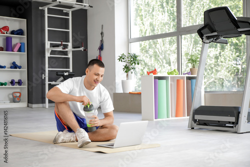 Sporty young man using laptop in gym