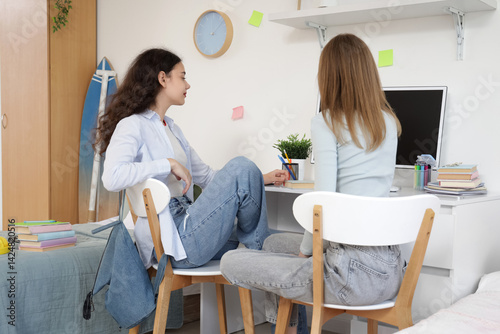 Teenage girls studying together in dorm room, collaborative learning and frie...