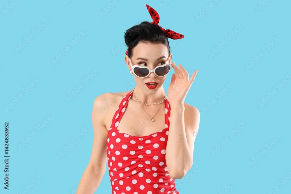 Young pin-up woman in sunglasses on blue background