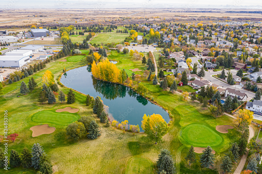 Fototapeta premium Golf course with a pond and a residential area in the background