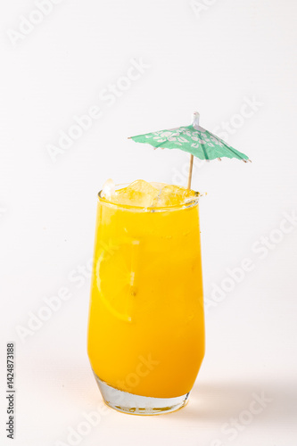 A glass of orange juice with a green umbrella on top. The umbrella is made of paper and is placed over the glass