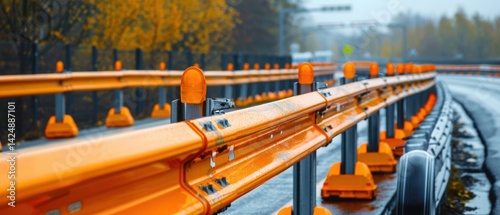 Traffic safety barrier installation process shows orange highway guardrail infrastructure detail with signal lights on wet asphalt.