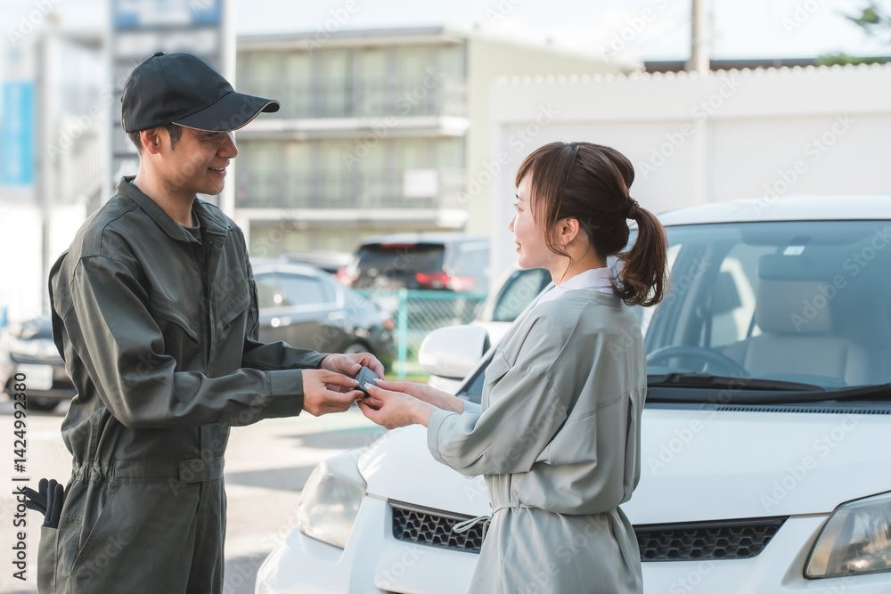 女性客から車の鍵を預かる自動車整備士の男性スタッフ
女性客から車の鍵を預かる自動車整備士の男性スタッフ