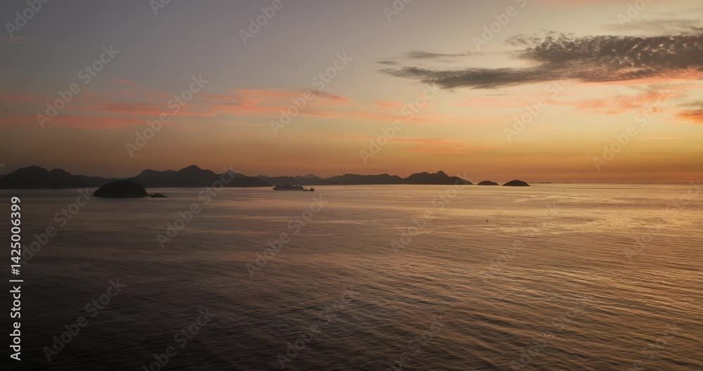 Flying above calm ocean towards mountains. Dawn with the first sight of lightness in the morning, passenger ship on the horizon