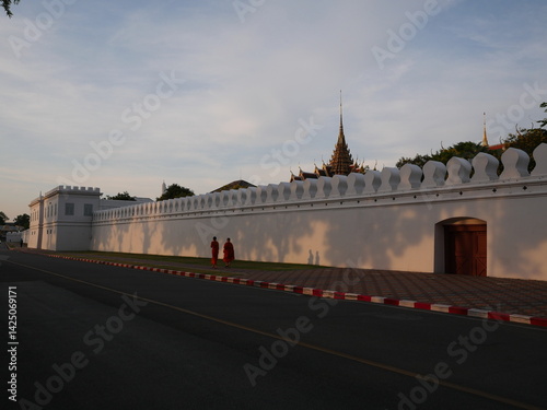 Monks walking along the outer wall of the Royal Palace in the evening.　Bangkok, Thailand