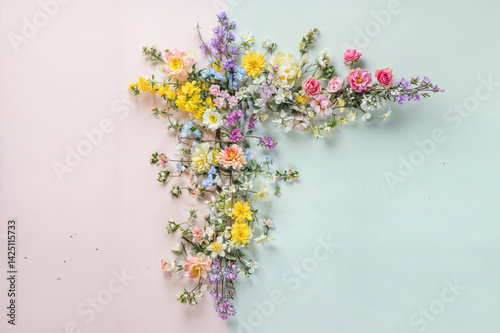 The image features a vibrant assortment of colorful flowers arranged in a corner shape against a pastel background divided into two colors, pink and light blue
